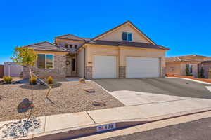 View of front of property featuring stucco siding, driveway, stone siding, a tile roof, and a garage