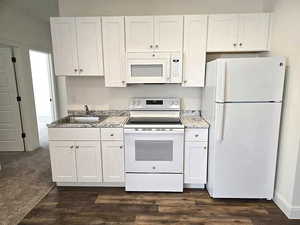 Kitchen with white cabinetry, white appliances, and dark wood finished floors