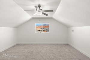 Bonus room featuring light colored carpet, vaulted ceiling, and ceiling fan