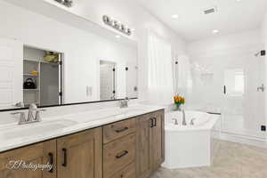 Full bath featuring a freestanding tub, double vanity, a marble finish shower, recessed lighting, and a spacious closet