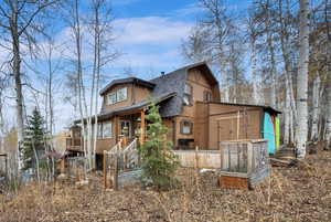 View of side of property featuring roof with shingles, a gambrel roof, a vegetable garden, and a wooden deck