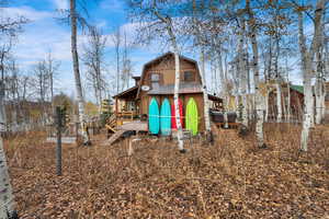 Back of property featuring a gambrel roof and a wooden deck