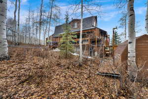 View of side of home featuring a shingled roof and mansard roof