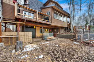 Back of property featuring roof with shingles, a wooden deck, and a sunroom