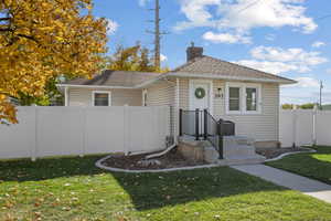 Bungalow-style home with a shingled roof and a chimney