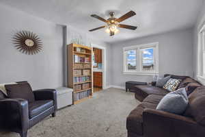 Living area with light colored carpet and a ceiling fan