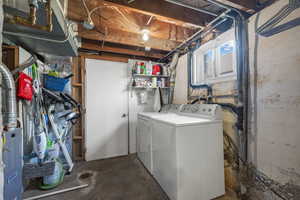 Laundry area with independent washer and dryer and unfinished concrete floors