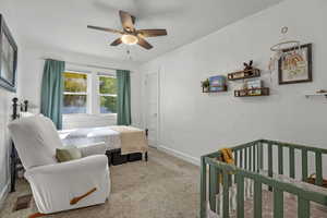Bedroom with carpet, a crib, and ceiling fan