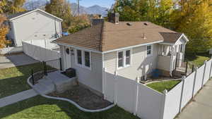 Back of property featuring a shingled roof, a fenced backyard, a mountain view, and a chimney
