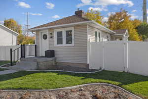 Bungalow featuring roof with shingles, a chimney, and a gate