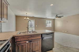 Kitchen featuring dishwashing machine, light colored carpet, range, a peninsula, and a chandelier