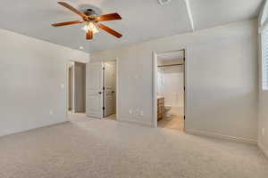 Unfurnished bedroom featuring light carpet, a ceiling fan, and ensuite bath