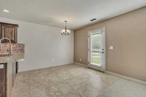 Unfurnished dining area featuring a chandelier and light tile patterned flooring