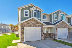 View of front of property with stone siding, a garage, driveway, and covered porch