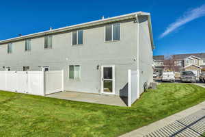 Back of house featuring a lawn and stucco siding