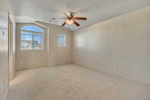 Spare room with light carpet, lofted ceiling, and a ceiling fan