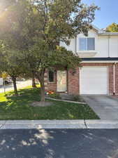 View of front of the home featuring a front yard, driveway, brick siding, and a garage