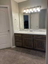 Ensuite bathroom with vanity and dark colored carpet