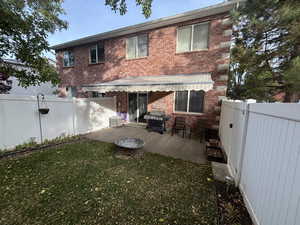 Retractable yawning. Back of house with a patio, a fenced backyard, and brick siding