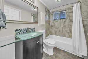 Full bathroom featuring a textured ceiling, shower / bath combo with shower curtain, vanity, and tile patterned floors