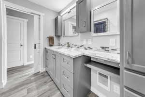 Bathroom featuring vanity, light wood-style flooring, and tasteful backsplash