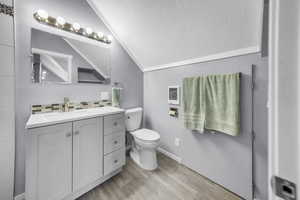 ADU above the garage. Bathroom with lofted ceiling, vanity, a textured ceiling, light wood-type flooring, and heating unit