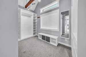 Mudroom featuring light colored carpet and high vaulted ceiling
