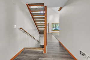 Stairs featuring wood finished floors and a towering ceiling
