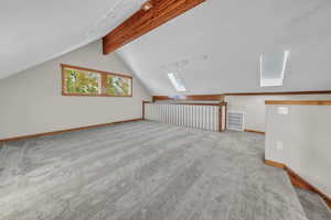 Additional living space featuring a skylight and light colored carpet