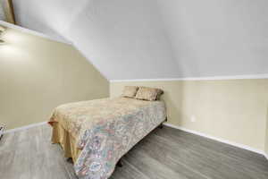 ADU above the garage. Bedroom with a textured ceiling, vaulted ceiling, and wood finished floors