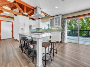 Kitchen featuring glass insert cabinets, white cabinets, backsplash, a breakfast bar area, and recessed lighting