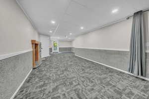 Below grade area featuring carpet, a paneled ceiling, wainscoting, and recessed lighting
