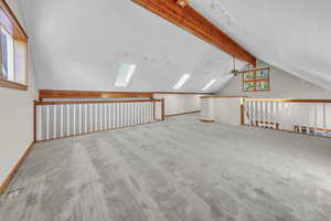 Bonus room featuring light carpet, a skylight, and a ceiling fan