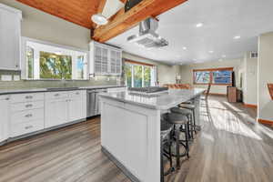 Kitchen with white cabinetry, a center island, beamed ceiling, a breakfast bar, and glass insert cabinets