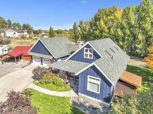View of front facade with a shingled roof, board and batten siding, covered porch, a garage, and a front lawn