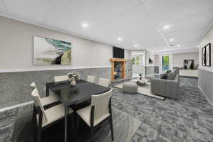 Dining area featuring wainscoting, dark carpet, a lit fireplace, a paneled ceiling, and recessed lighting