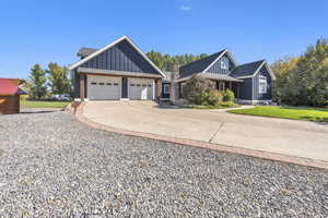 View of front of home with board and batten siding, concrete driveway, and roof with shingles