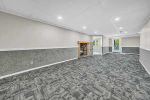 Basement featuring dark colored carpet, recessed lighting, wainscoting, and a drop ceiling