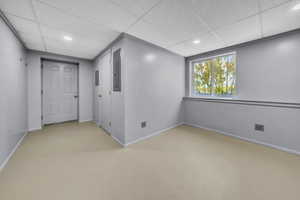 Empty room with a paneled ceiling, recessed lighting, and light colored carpet
