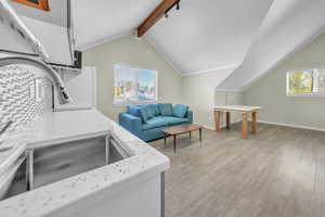 ADU above the garage. Kitchen featuring plenty of natural light, light wood-style flooring, backsplash, and light stone countertops