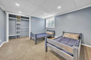 Bedroom with a drop ceiling, light colored carpet, recessed lighting, and a closet