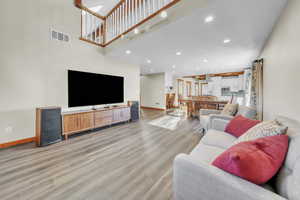 Living area with light wood-style flooring, recessed lighting, and a high ceiling