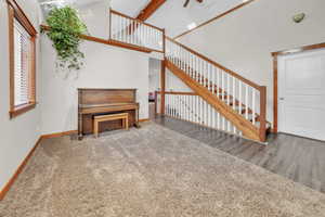 Staircase featuring high vaulted ceiling, carpet floors, and beamed ceiling
