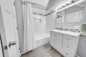 ADU above the garage. Bathroom featuring vanity, light wood finished floors, shower / bath combo with shower curtain, and decorative backsplash