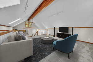 Carpeted living area featuring rail lighting, a skylight, and ceiling fan