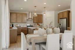 Kitchen with a kitchen island, light countertops, decorative light fixtures, brown cabinets, and wall chimney range hood