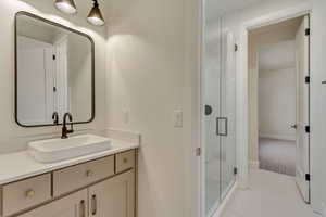 Full bath with vanity, a shower stall, and light tile patterned flooring