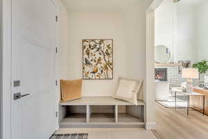 Mudroom with a glass covered fireplace and light wood-type flooring