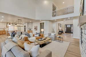 Living area with recessed lighting, light wood-style flooring, a chandelier, and a high ceiling
