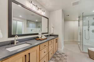 Bathroom featuring double vanity, a shower stall, recessed lighting, and light tile patterned floors